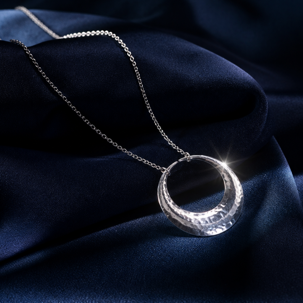 Light moving across a silver crescent pendant